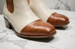 Paire de bottines en cuir San Marina photographiée sur surface en marbre blanc, détail de coutures et qualité du cuir